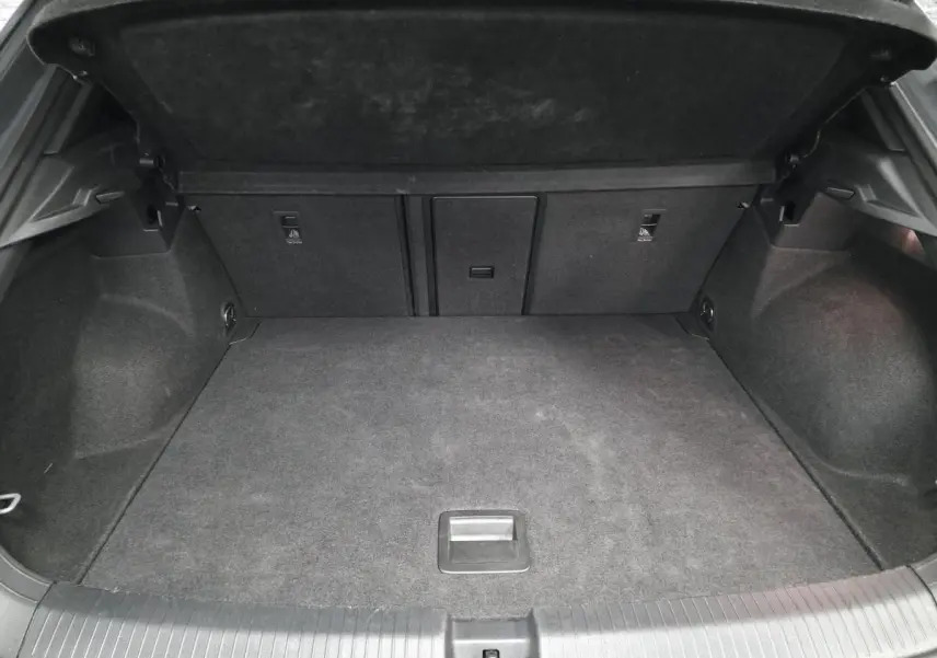 Coffre ouvert vu de l'arrière d'un Volkswagen T-Roc gris, montrant un espace de chargement propre et spacieux.
