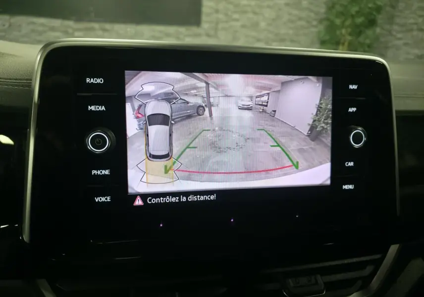Écran tactile intérieur affichant la caméra de recul du Volkswagen T-Roc gris, vue arrière avec lignes de guidage vertes et rouges.