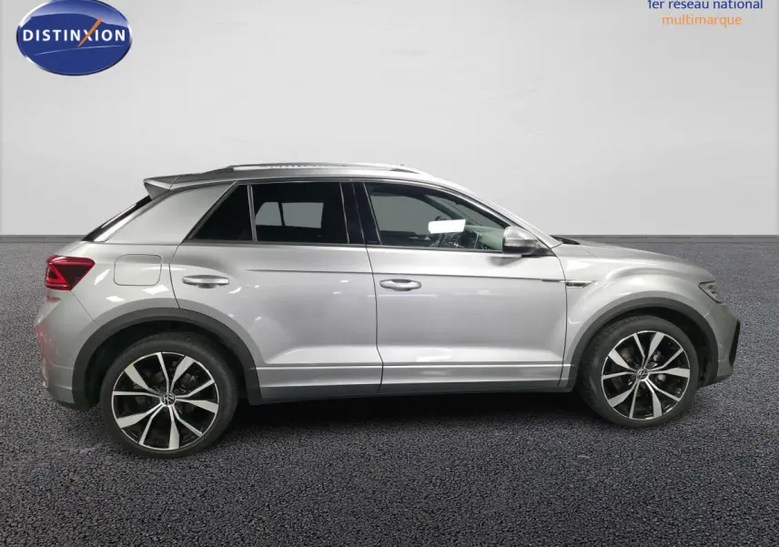 Vue de profil côté gauche d'un Volkswagen T-Roc gris métallisé avec jantes alliage 19 pouces et détails R-Line.