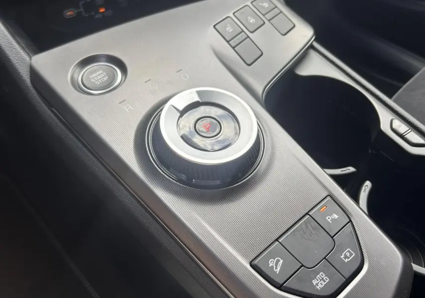 Gros plan sur la console centrale du Kia Sportage noir 2026, avec molette de sélection de vitesse et boutons de contrôle.