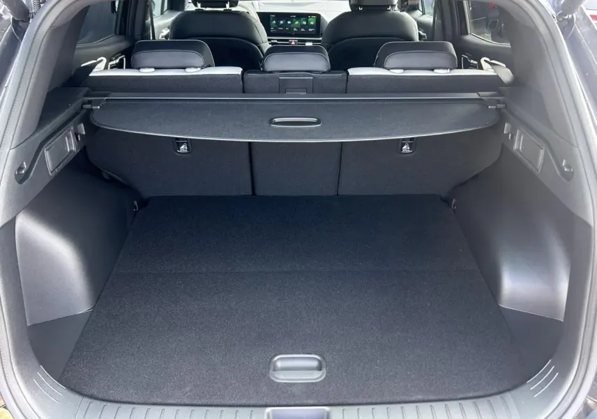 Vue arrière du coffre noir du Kia Sportage 2026 avec cache-bagages et sièges arrière rabattables visibles.