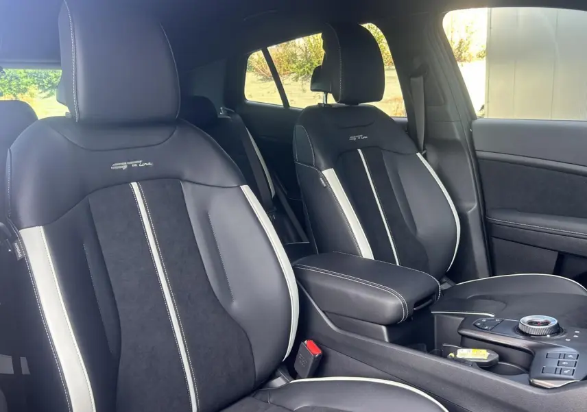 Vue intérieure sur les sièges avant bi-ton noir et gris du KIA Sportage 2026 GT-line avec accoudoir central.