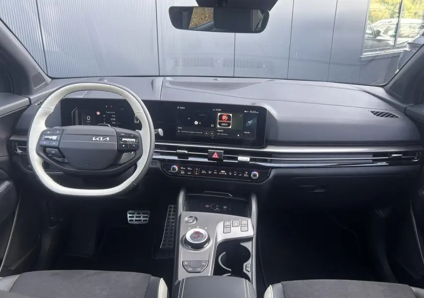 Vue intérieure avant du tableau de bord noir du Kia Sportage 2026 avec écran tactile large et volant bi-ton.