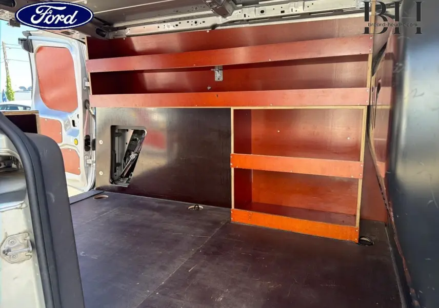 Vue intérieure arrière du Ford Transit Connect gris lunaire, montrant l’espace de chargement avec étagères en bois intégrées.