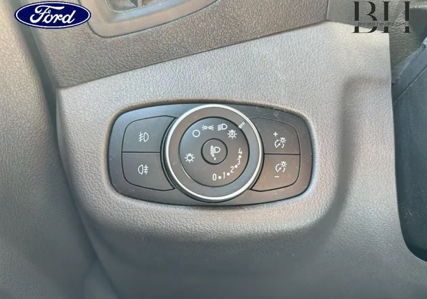 Gros plan sur la commande des phares du Ford Transit Connect gris lunaire, tableau de bord en plastique noir texturé.