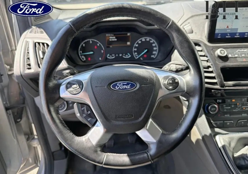 Vue intérieure centrée sur le volant en cuir noir du Ford Transit Connect 2022 avec tableau de bord et écran tactile visibles.