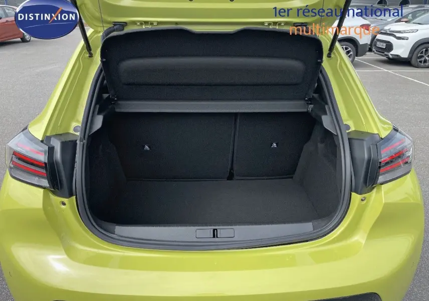 Coffre ouvert vu de l'arrière d'une Peugeot 208 jaune Agueda Metal, montrant l'espace de chargement vide.
