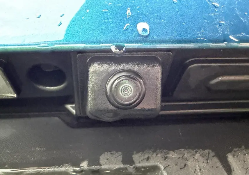 Gros plan sur la caméra de recul noire intégrée dans la partie arrière bleu Zanzibar métallisé du Renault Arkana 2025.