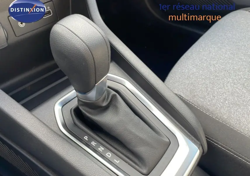 Gros plan sur le levier de vitesse automatique en cuir noir de la Renault Clio 2025, intérieur tissu gris.