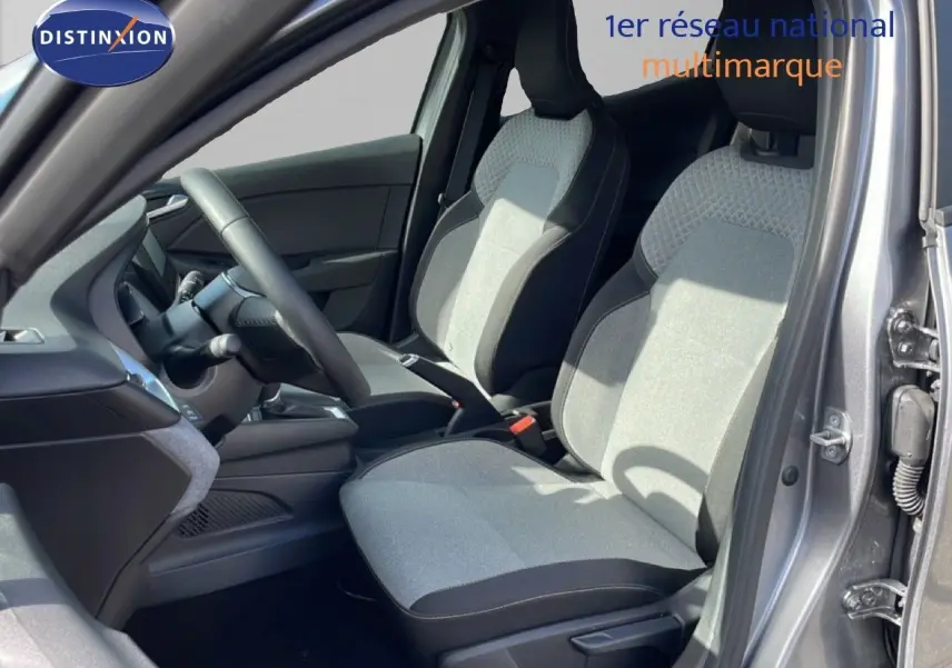 Vue intérieure côté conducteur de la Renault Clio 2025 gris schiste métal, sièges tissu bicolore et volant cuir multifonction.