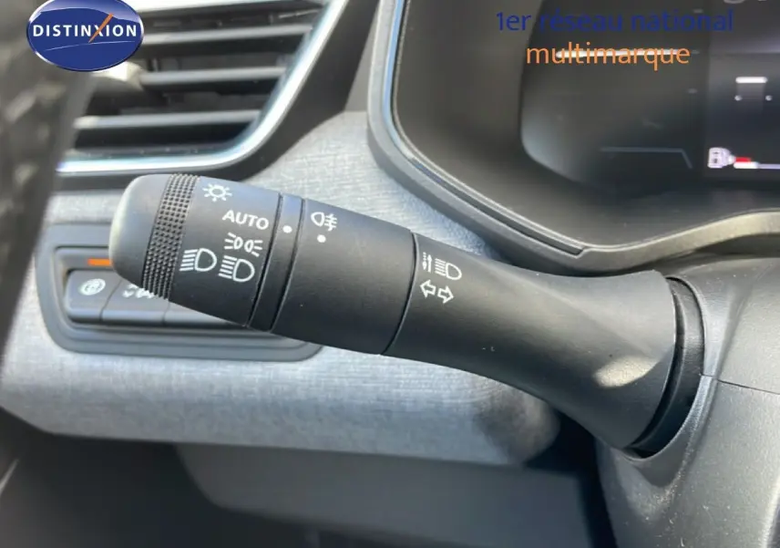 Gros plan sur la commande des feux et clignotants à gauche du volant dans l’habitacle gris de la Renault Clio 2025.