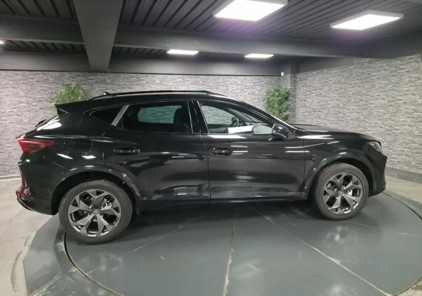 Vue de profil côté gauche du CUPRA Formentor noir 2025 dans un showroom avec jantes alliage et toit panoramique.