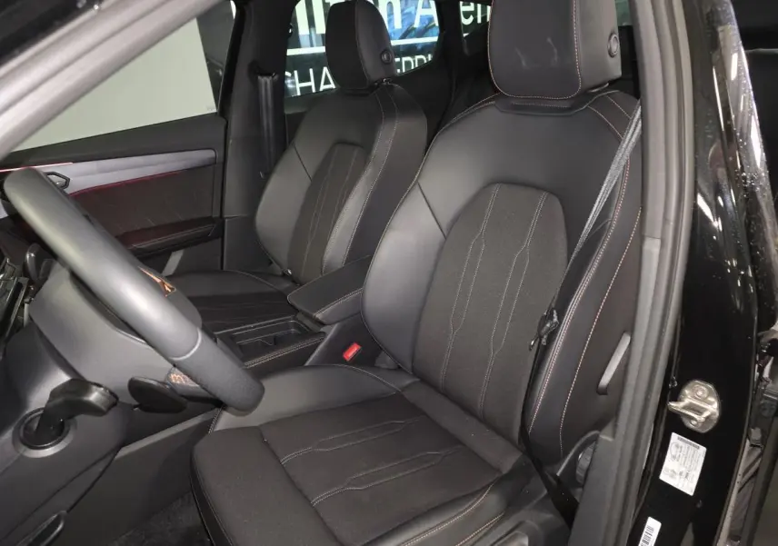 Vue intérieure côté conducteur du CUPRA Formentor noir, sièges sport bimatière avec surpiqûres cuivrées et volant cuir.