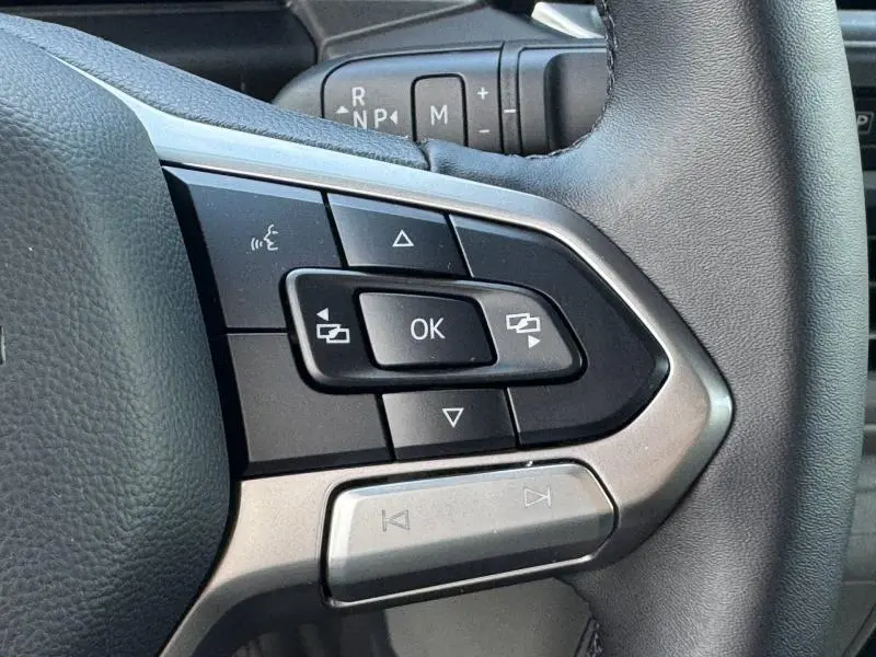 Gros plan sur les commandes multifonctions à droite du volant cuir du Volkswagen Transporter FGN 2025 noir.