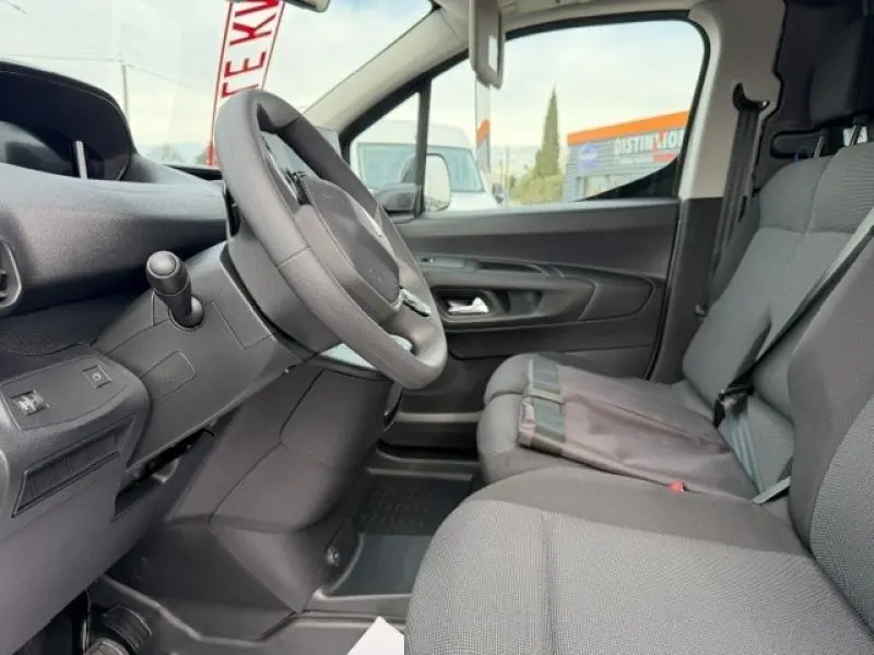Vue intérieure côté conducteur du Peugeot Partner XL 2025, sièges gris et volant multifonction visible.