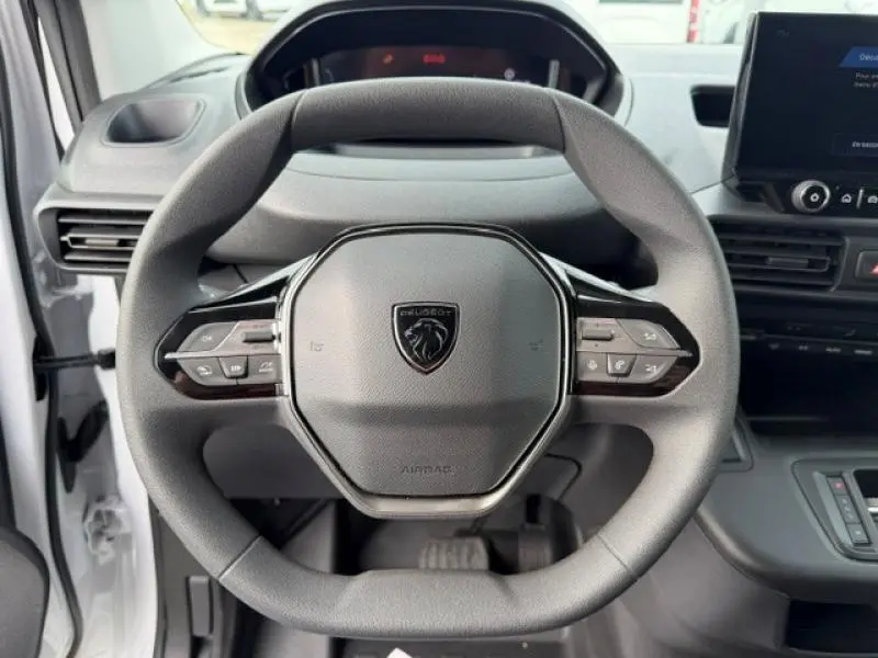 Vue rapprochée du volant multifonction noir du Peugeot Partner XL 2025, avec tableau de bord et écran tactile visibles.