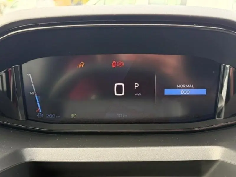Vue rapprochée du tableau de bord numérique du Peugeot Partner blanc, affichant la vitesse à 0 km/h en mode Éco.