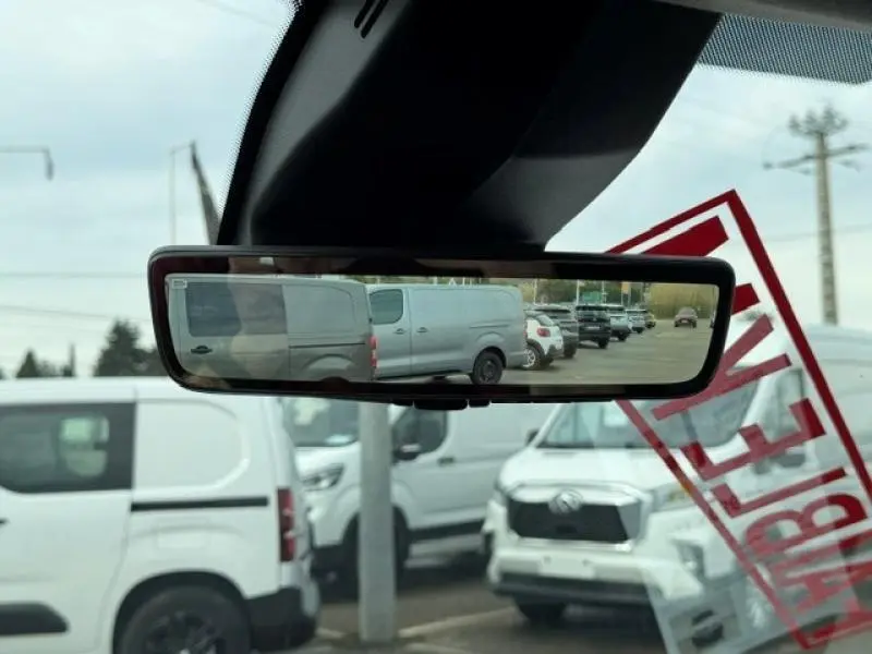 Vue dans le rétroviseur intérieur montrant plusieurs utilitaires blancs dont un Peugeot Partner XL 950kg Diesel en arrière-plan.