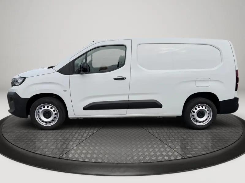 Vue de profil côté gauche d'un utilitaire Peugeot Partner XL blanc Icy avec porte latérale coulissante et protections noires.