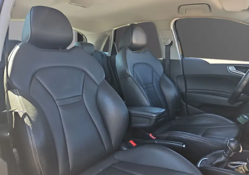 Vue intérieure de l’Audi A1 Sportback 2016 montrant les sièges baquets en cuir noir avec accoudoir central et volant sport.