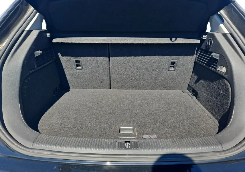 Coffre ouvert vu de l'arrière d'une Audi A1 Sportback noire, montrant un espace de chargement propre et bien fini.