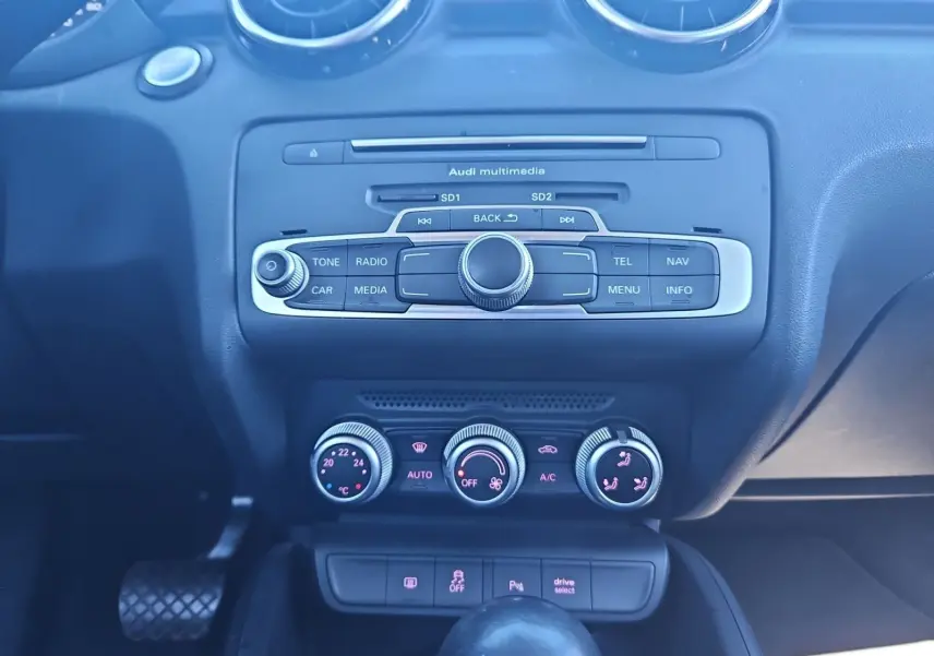 Vue rapprochée du tableau de bord noir de l’Audi A1 Sportback 2016, montrant la console multimédia et les commandes de climatisation.