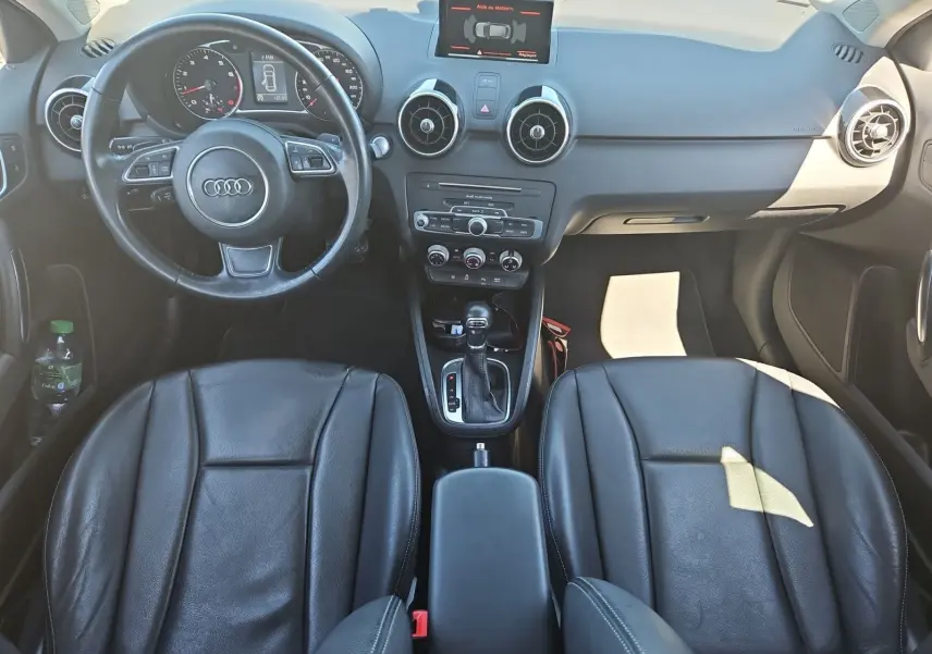 Vue intérieure frontale de l’Audi A1 Sportback 2016 avec sièges baquets cuir noir et console centrale avec boîte auto.
