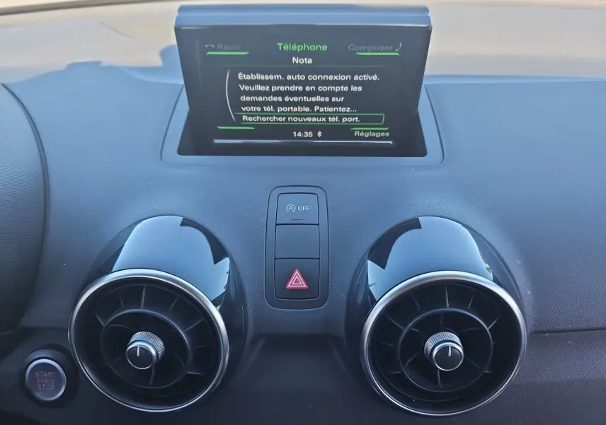 Vue rapprochée du tableau de bord noir de l'Audi A1 Sportback 2016, avec écran tactile et aérateurs ronds chromés.