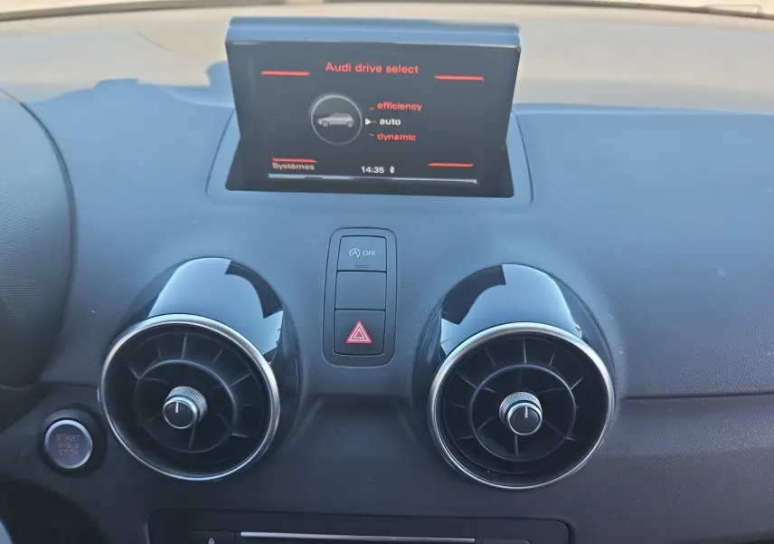 Vue rapprochée du tableau de bord de l'Audi A1 Sportback 2016, avec écran central et aérateurs ronds noirs.