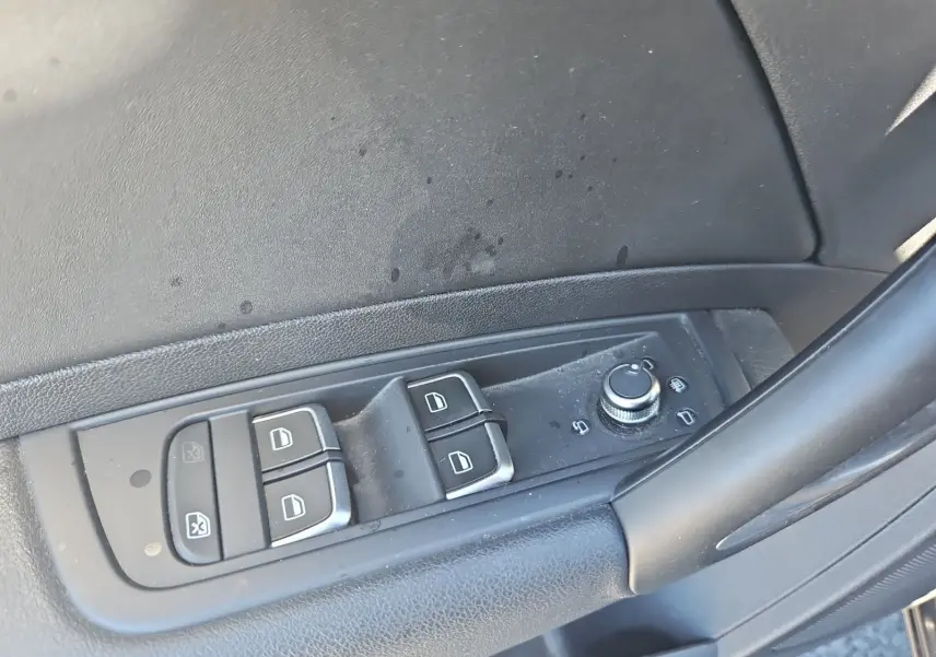 Gros plan sur les commandes des vitres et des rétroviseurs côté conducteur de l’Audi A1 Sportback noire de 2016.