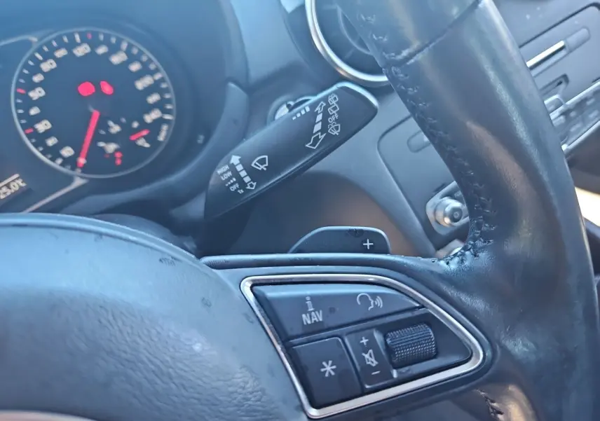 Gros plan sur le volant cuir noir d’Audi A1 Sportback 2016 avec commandes audio et palettes au volant visibles.