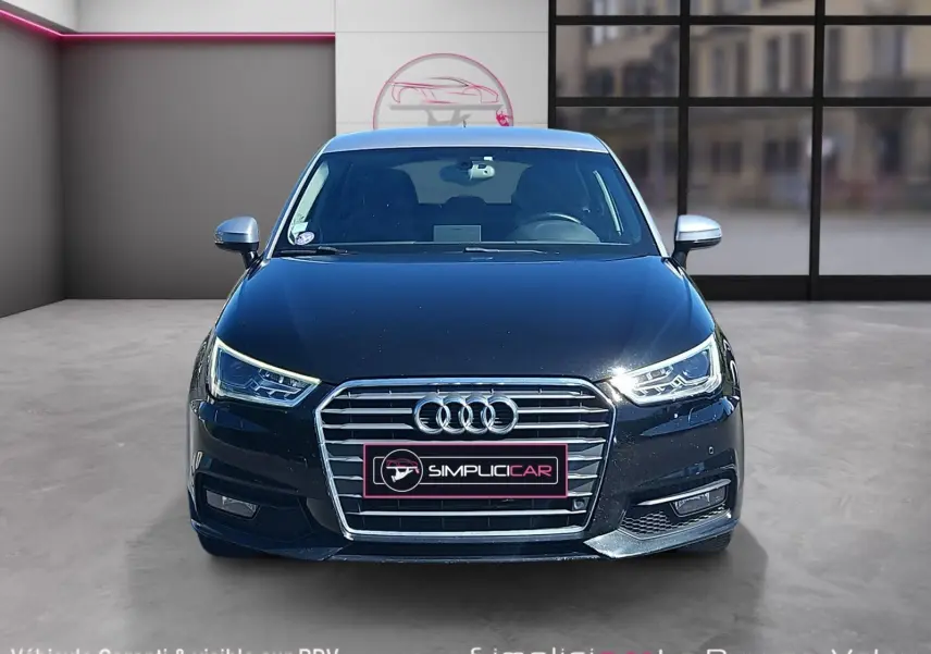 Vue avant d'une Audi A1 Sportback noire de 2016 avec calandre chromée et phares LED allumés.