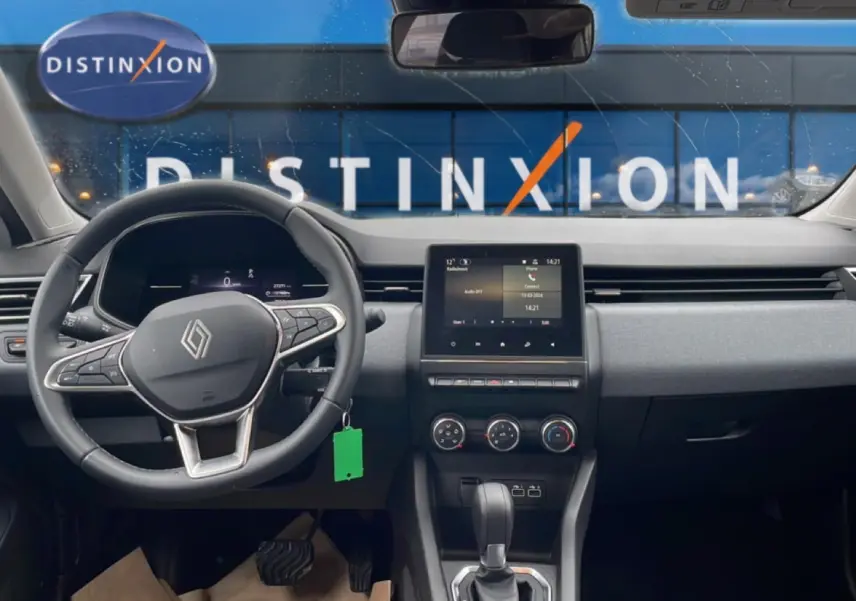 Vue intérieure avant du tableau de bord de la Renault Clio V blanche avec écran tactile et volant multifonction.