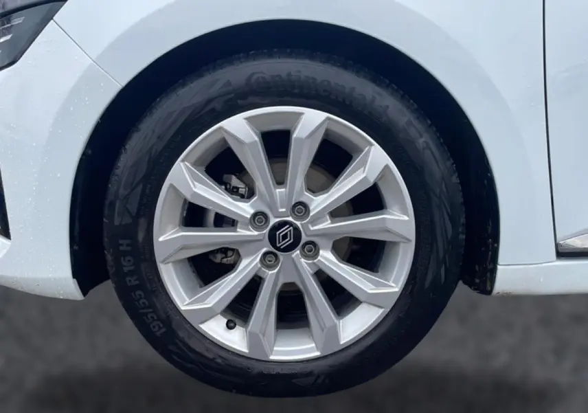 Gros plan sur la roue avant droite de la Renault Clio V blanche, avec jante alliage 16 pouces et logo central.