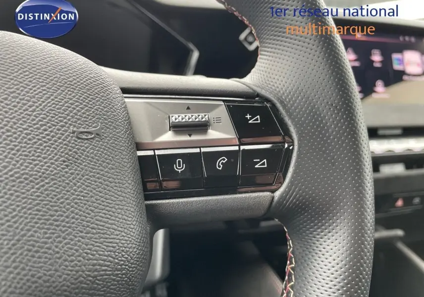 Gros plan sur les commandes du volant en cuir perforé d'une DS4 2024 gris laqué, mettant en valeur les boutons multifonctions.