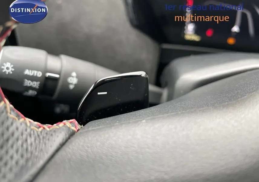 Gros plan sur la palette de changement de vitesse noire côté droit du volant perforé avec surpiqûres rouges du DS4 2024.