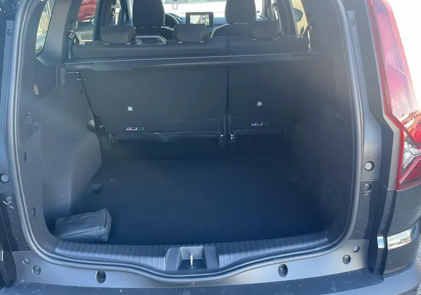 Coffre ouvert d'un Dacia Jogger noir nacré 2024, vue arrière montrant banquette rabattable et tablette cache-bagages.