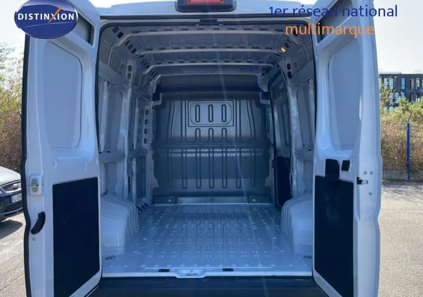 Vue arrière du Peugeot Boxer Fourgon blanc banquise 2025 avec portes arrière ouvertes montrant l'espace de chargement vide.