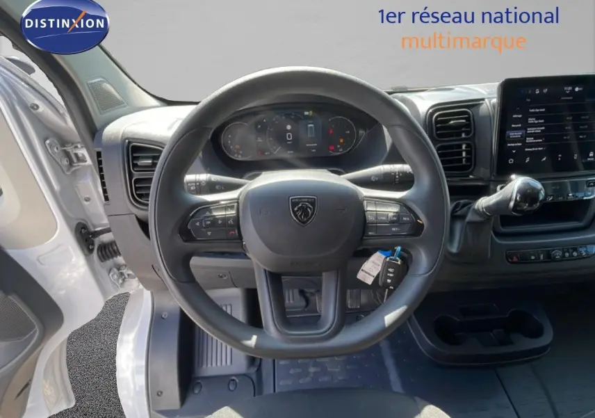Vue intérieure centrée sur le volant Peugeot d'un Boxer Fourgon blanc banquise avec tableau de bord numérique et écran tactile.