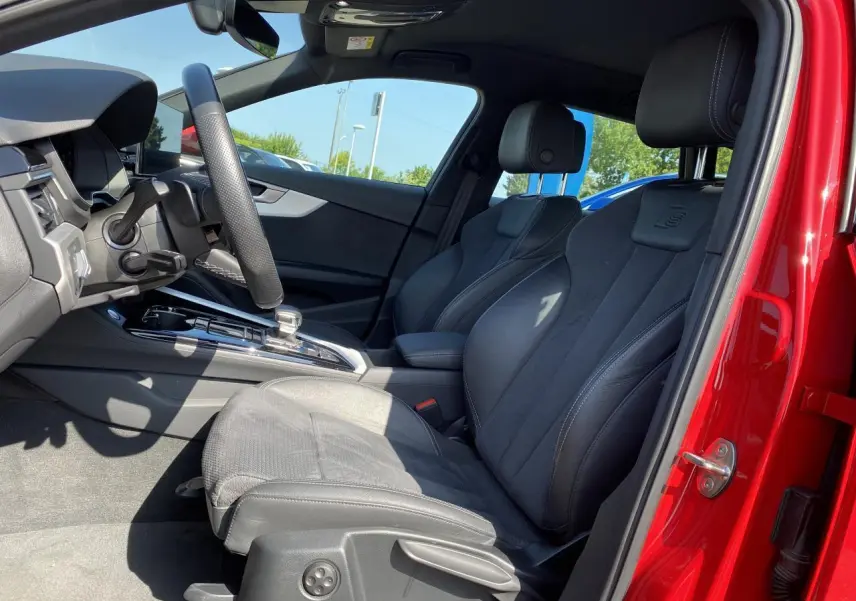 Vue intérieure côté conducteur de l'Audi A4 Avant S line rouge tango, sièges sport en cuir avec logo S embossé.