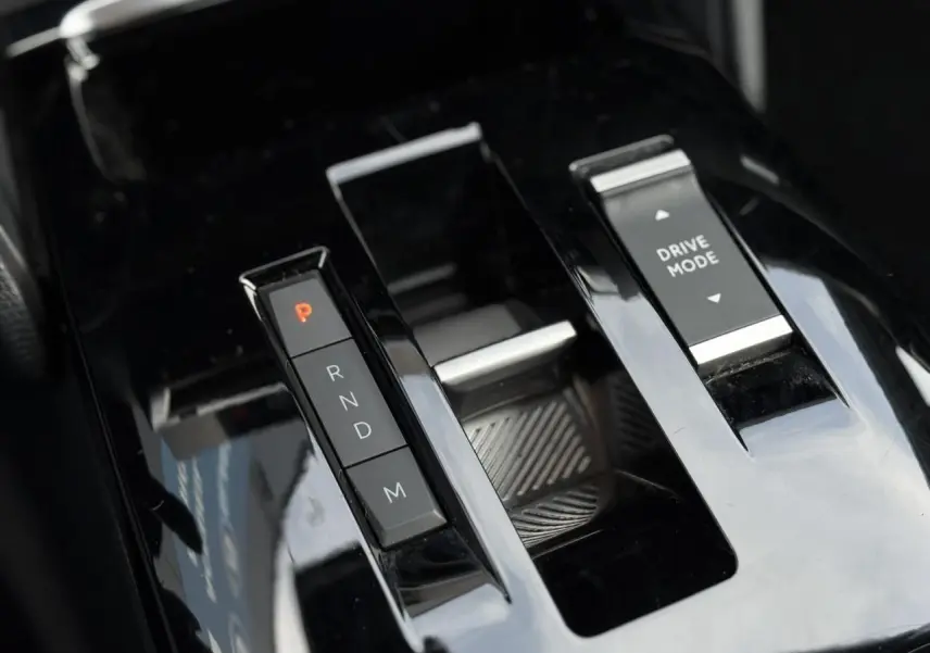 Gros plan sur la console centrale noire brillante avec commandes de boîte auto et mode de conduite de la Citroën C4 X.