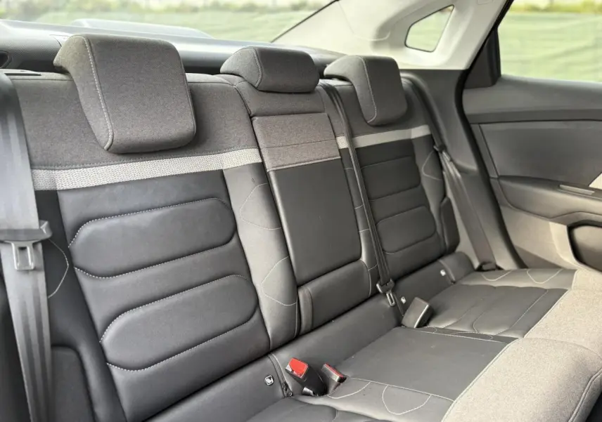 Vue intérieure des sièges arrière en tissu gris chiné et toile noire du Citroën C4 X 2024, avec ceintures et appuie-têtes.