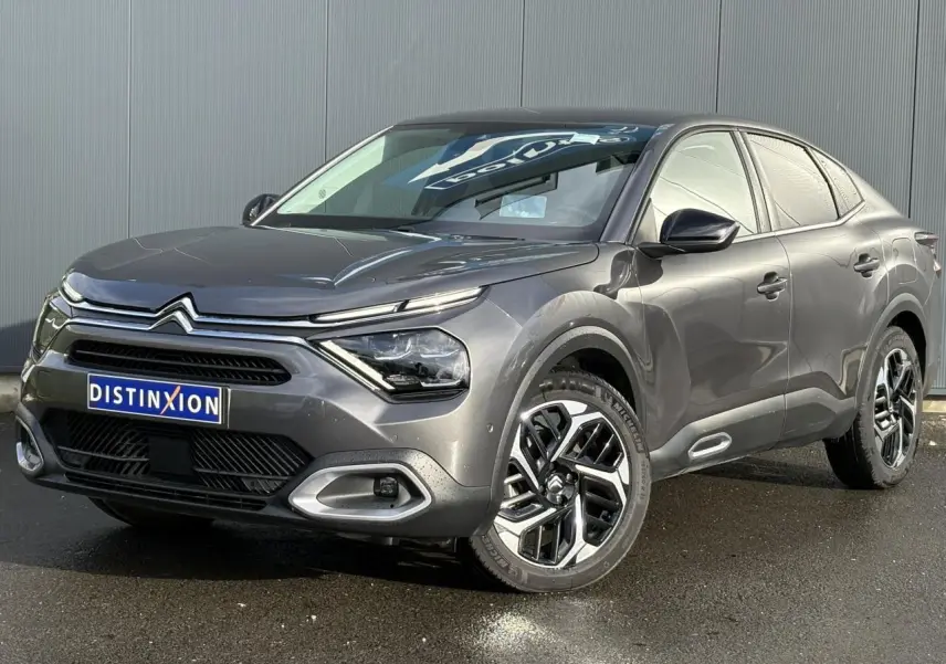 Citroën C4 X gris Platinium en 3/4 avant droit, avec jantes alliage et signature lumineuse LED distinctive.