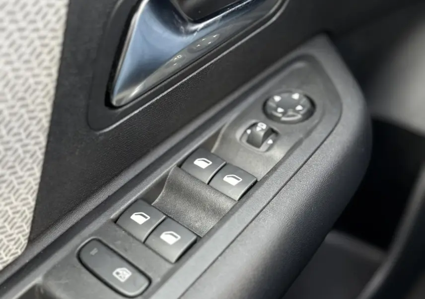 Gros plan sur les commandes de lève-vitres et rétroviseurs côté conducteur d'une Citroën C4 X gris Platinium.