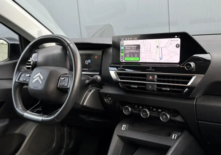Vue intérieure côté conducteur du tableau de bord noir avec écran tactile 10 pouces affichant la navigation du Citroën C4 X 2024.