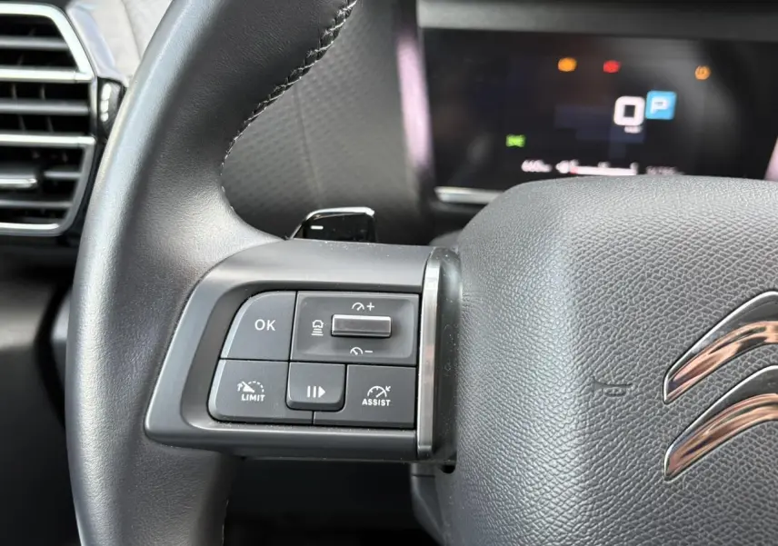 Gros plan sur le côté gauche du volant cuir noir de la Citroën C4 X 2024 avec commandes du régulateur adaptatif.