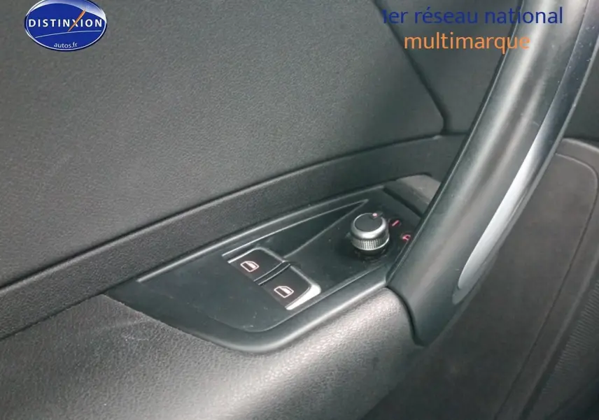 Gros plan sur les commandes des vitres électriques et rétroviseurs sur la porte côté conducteur d'une Audi A1 blanche.