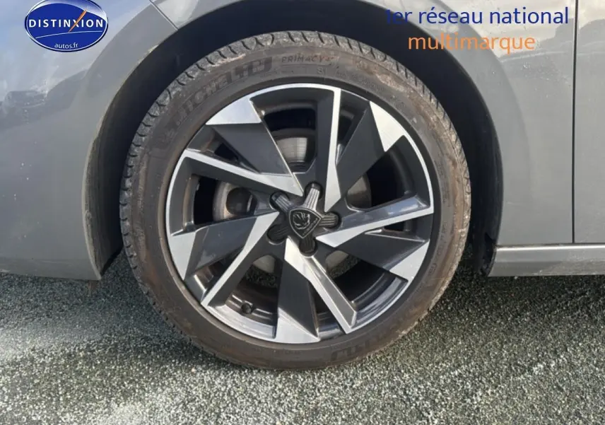 Gros plan sur la roue avant gauche avec jante alu bicolore du Peugeot 308 gris sélénite 2024.