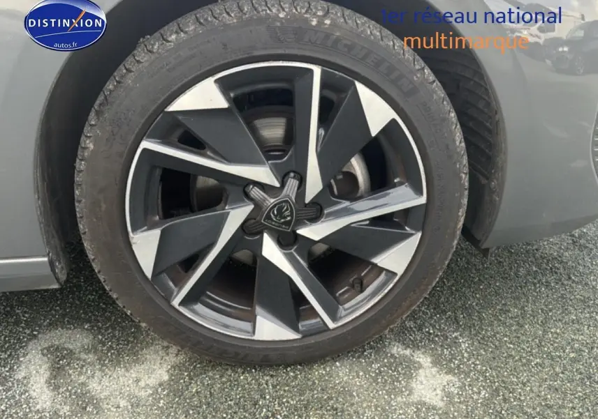 Gros plan sur la roue avant droite avec jante alu bicolore du Peugeot 308 gris sélénite 2024.