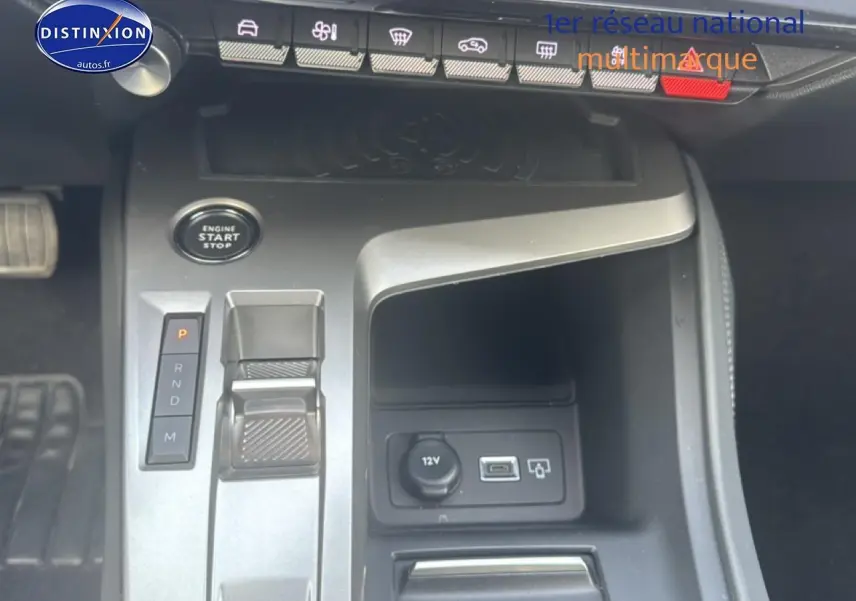 Vue rapprochée de la console centrale grise de la Peugeot 308 2024 avec bouton start/stop et commandes de boîte auto.